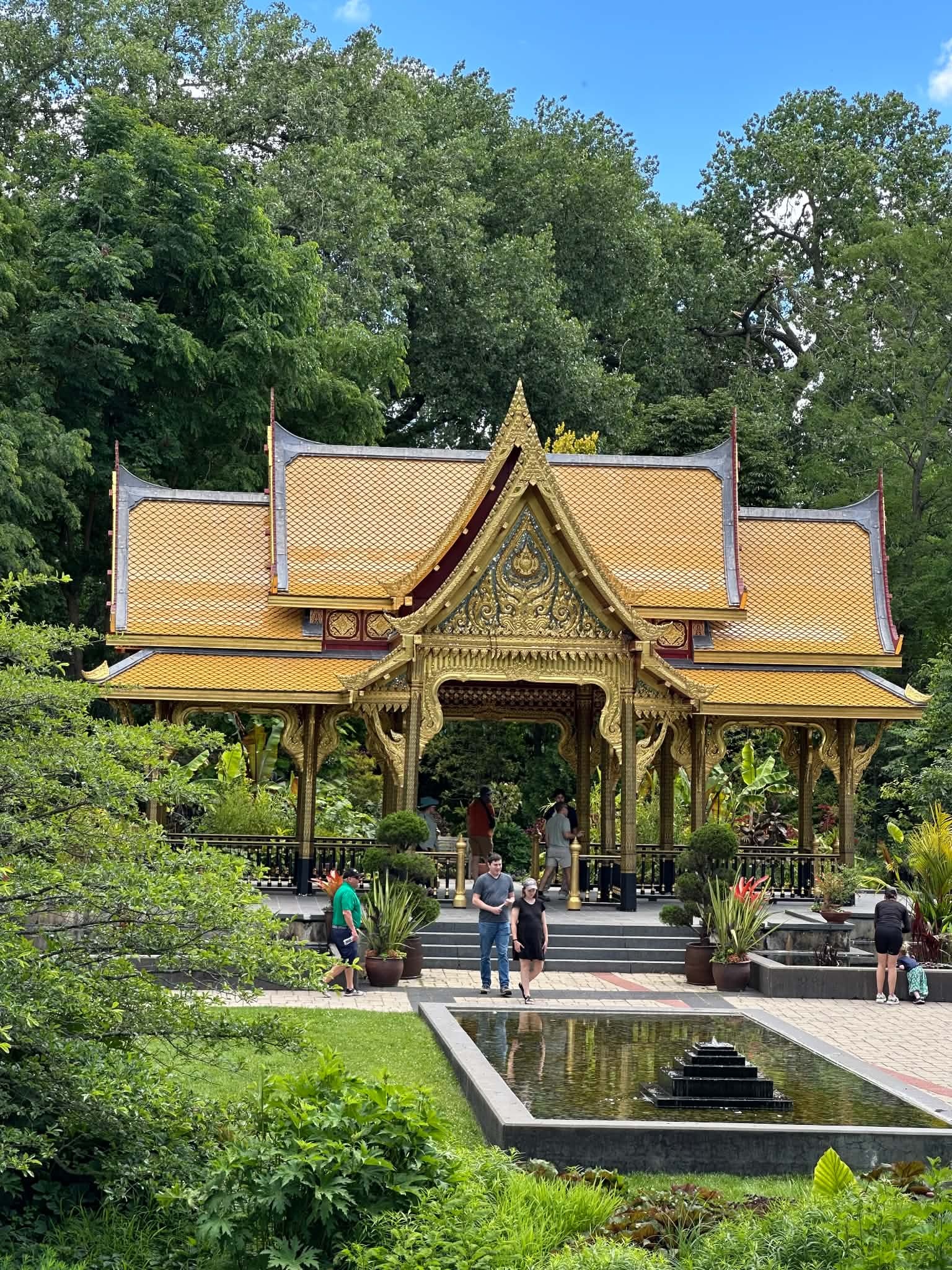 Royal Thai Pavilion at Olbrich Botanical Gardens with blue sky, greenery, and the pond area.